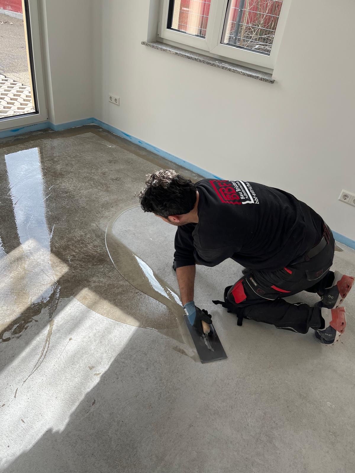 BBF-Mitarbeiter glättet frisch verlegten Estrich auf einer Baustelle
